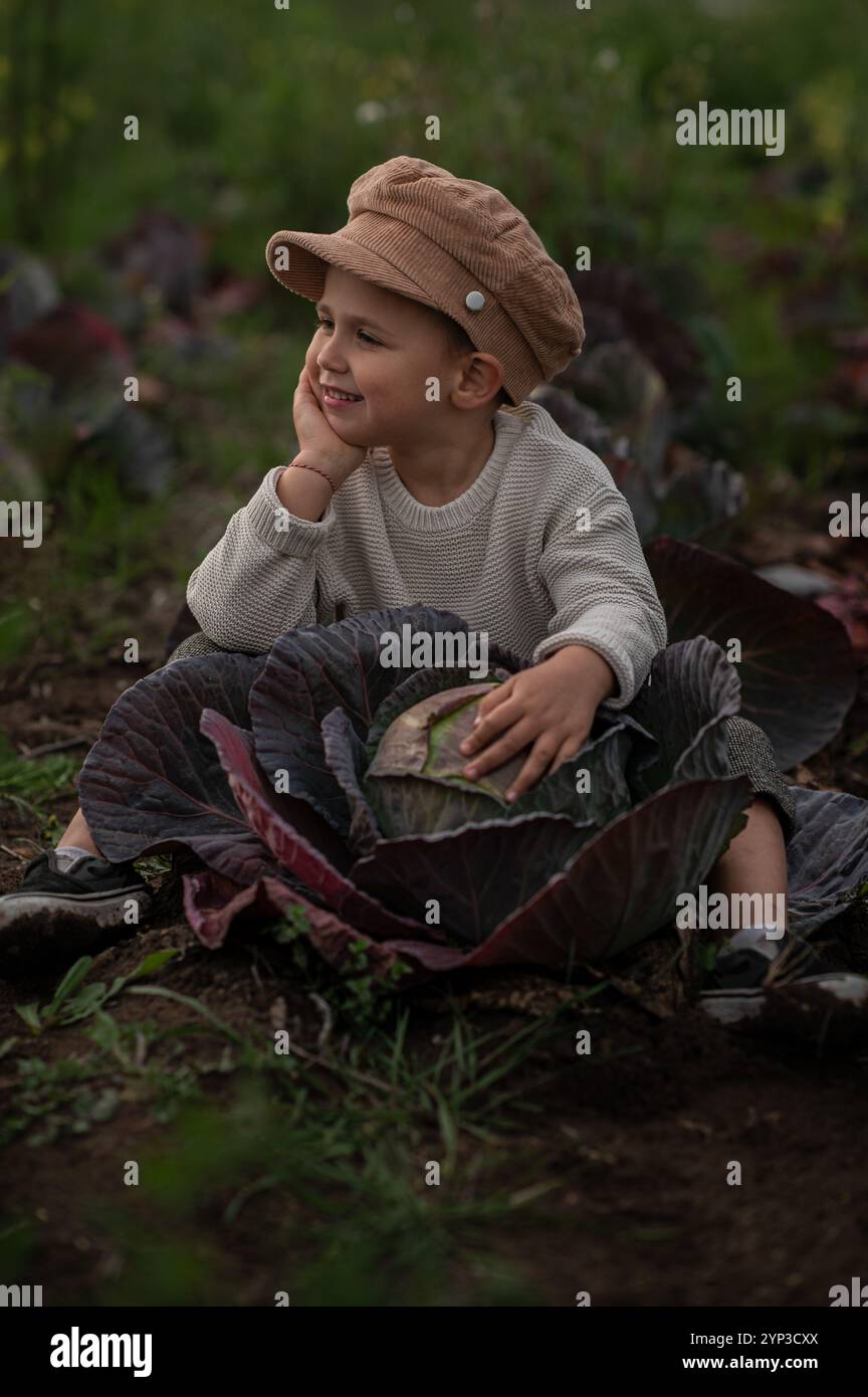 il bambino è seduto in un cavolo con cappello Foto Stock