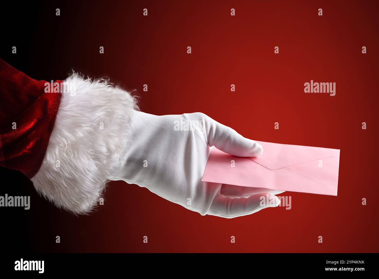 Babbo Natale indossa tuta e guanti con busta rosa con lettera e lista dei regali su sfondo rosso isolato Foto Stock