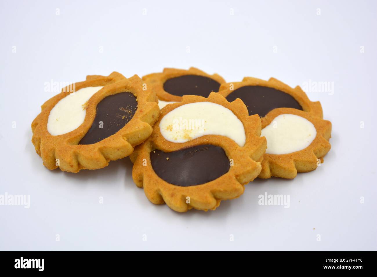 Biscotto di sicurezza sotto forma di sole con stucco bianco e cioccolato, dolce sotto forma di due gocce poste su fondo bianco. Foto Stock