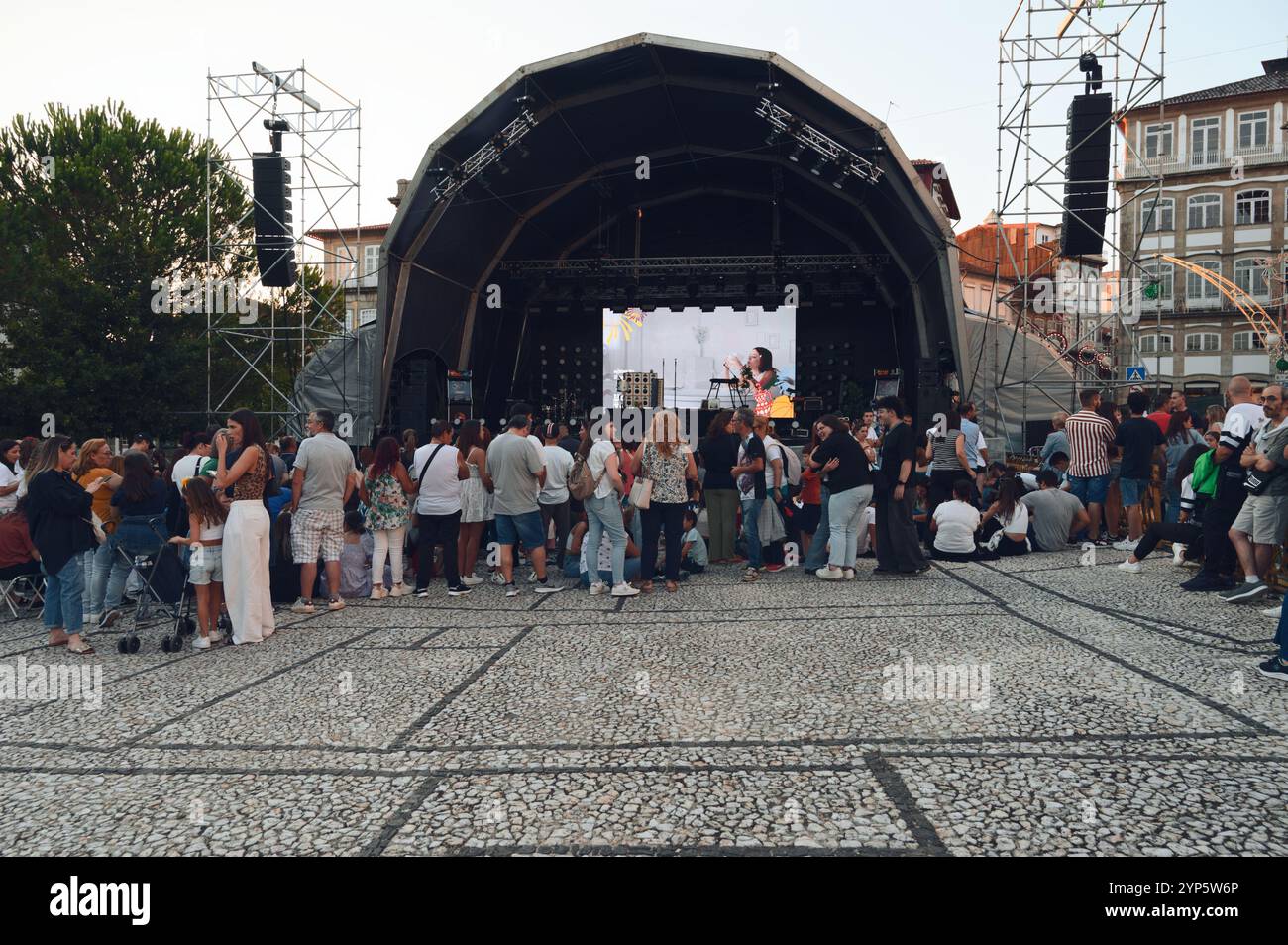 La folla si riunisce su un palco all'aperto durante i vivaci festival della città di Guimarães Foto Stock