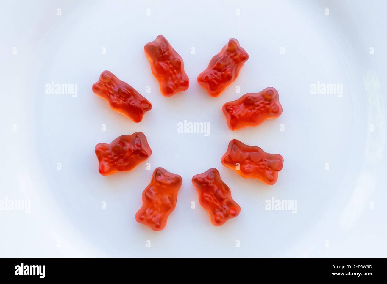 studio girato dall'alto di un cerchio di orsi di gelatina rossa. Si trova su uno sfondo bianco pulito. Concetto di mangiare dolce, cose dolci e carine ed eccessi su Foto Stock
