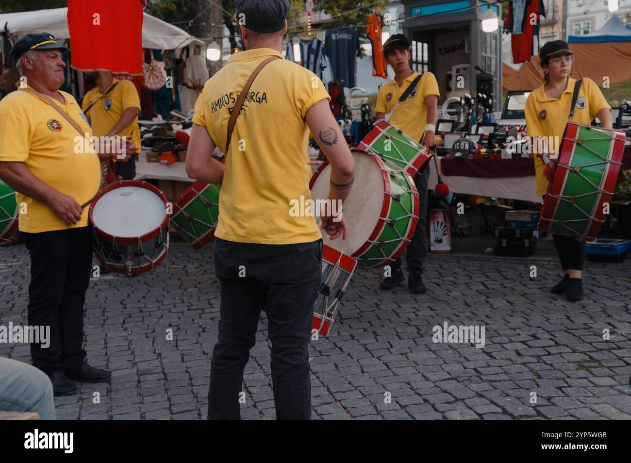 I batteristi in uniformi gialle vivaci stimolano il mercato durante le celebrazioni della città Foto Stock
