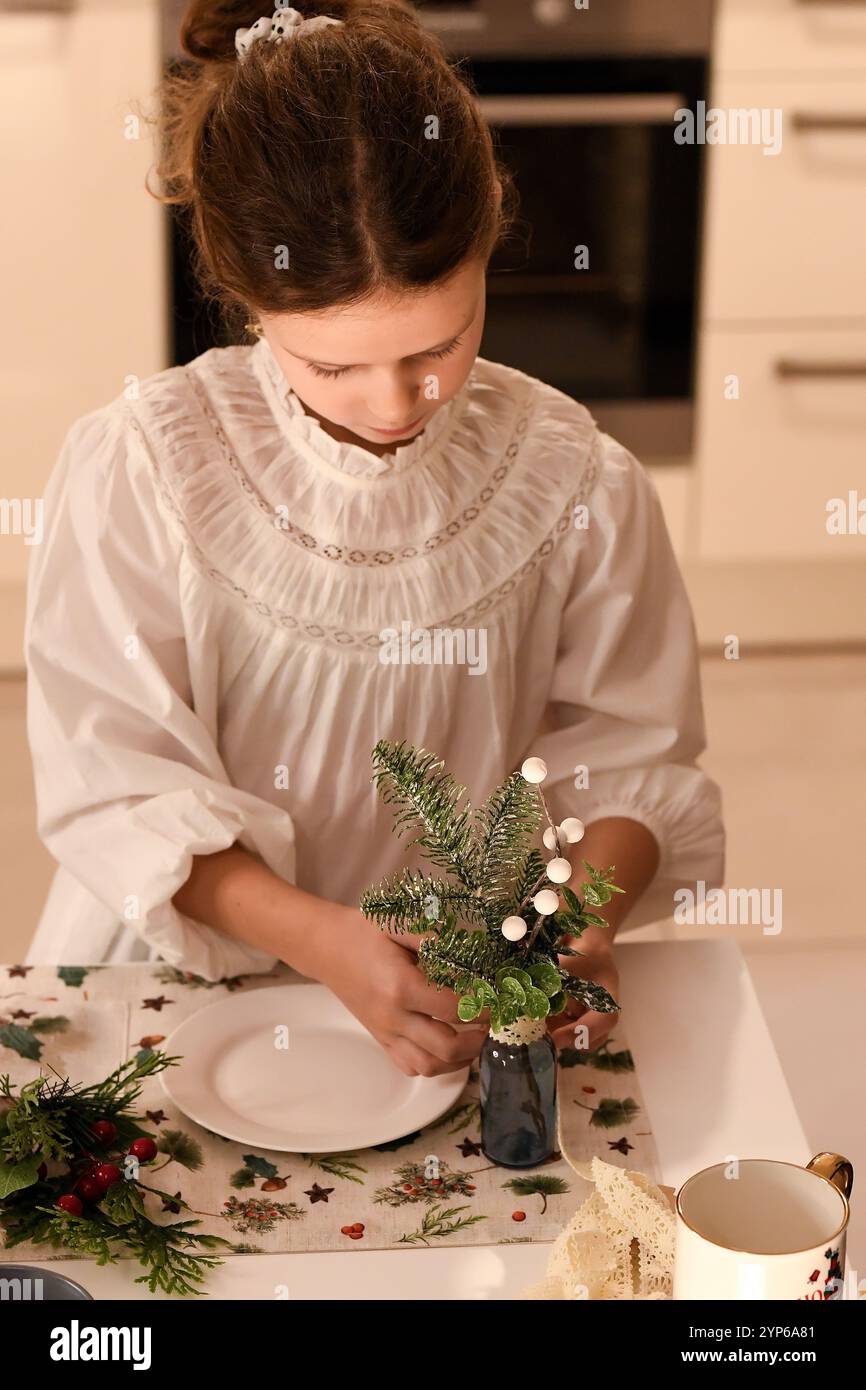 Nell'immagine, una ragazza vestita con una camicetta leggera arricciata sta decorando un tavolo. Foto Stock