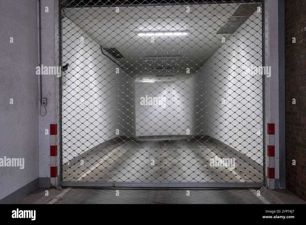 Spazio industriale chiuso con cancello metallico e illuminazione superiore Foto Stock