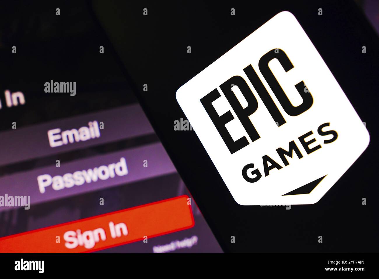 In questa immagine, il logo Epic Games viene visualizzato sullo schermo di uno smartphone, accanto a una schermata di accesso, con e-mail, password e accesso Foto Stock