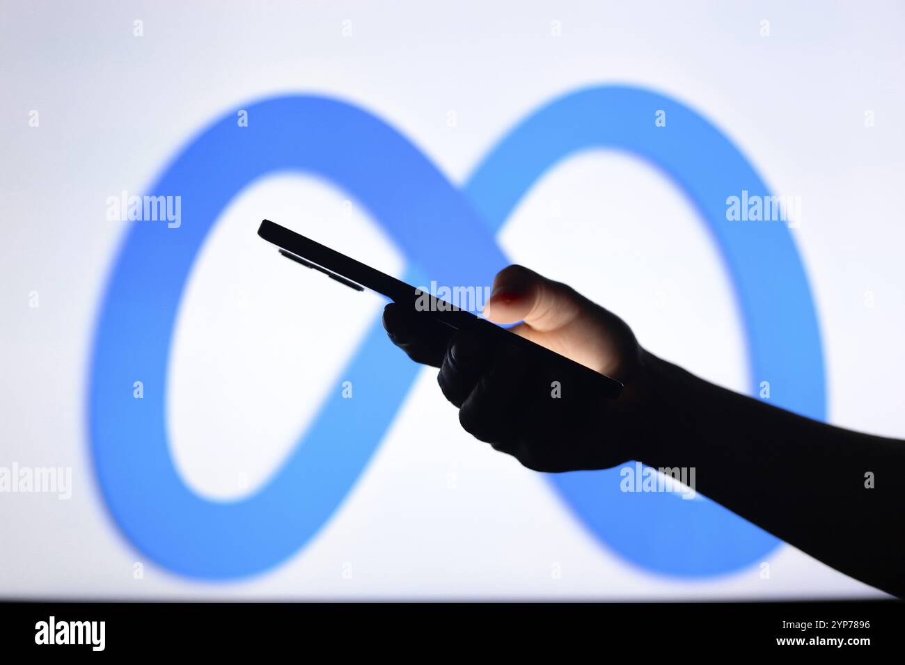 logo visualizzato sullo sfondo di una mano sagomata che regge uno smartphone Foto Stock