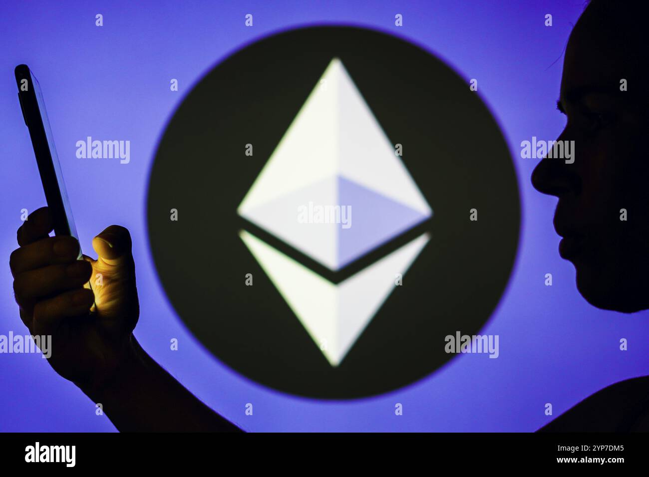 In questa foto, la silhouette di una donna contiene uno smartphone con il logo Ethereum sullo sfondo Foto Stock