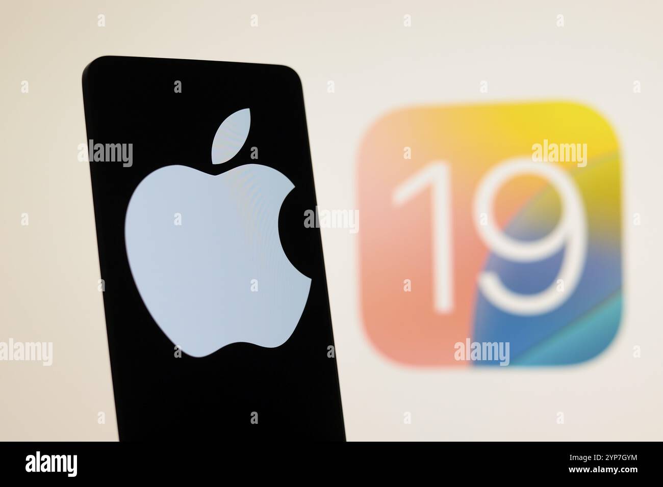 In questa immagine, il logo Apple visualizzato su uno smartphone con il logo iOS 19 sullo sfondo Foto Stock