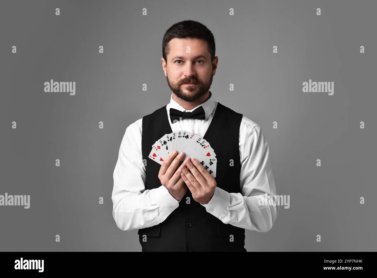Croupier professionale con carte da gioco su sfondo grigio Foto Stock