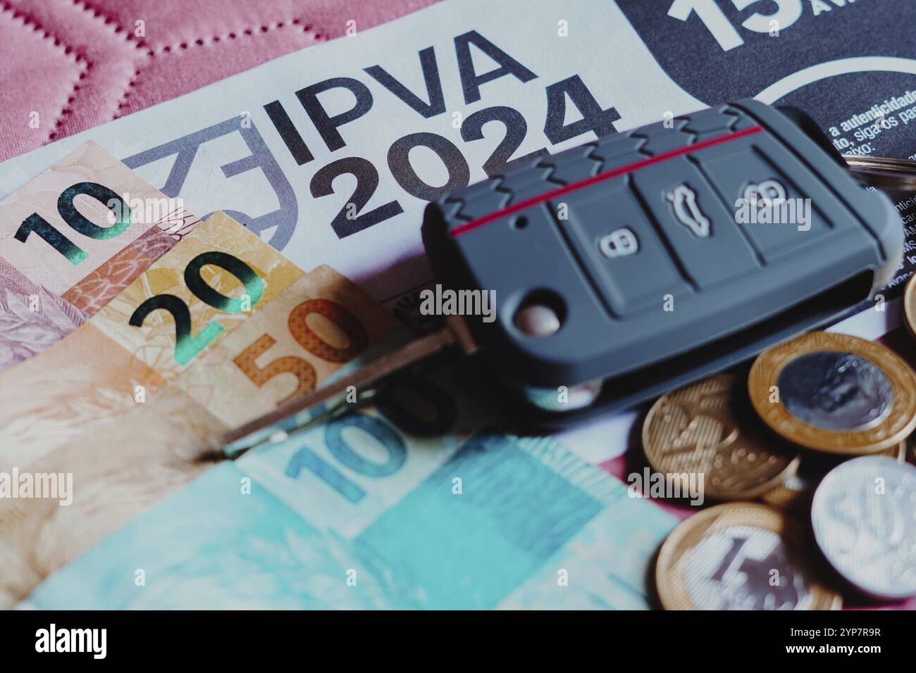 In questa foto è illustrata la ricevuta di pagamento IPVA (impulso sobre a Propriedade de Veiculos Automotores) accanto alle banconote e monete brasiliane in denaro reale Foto Stock