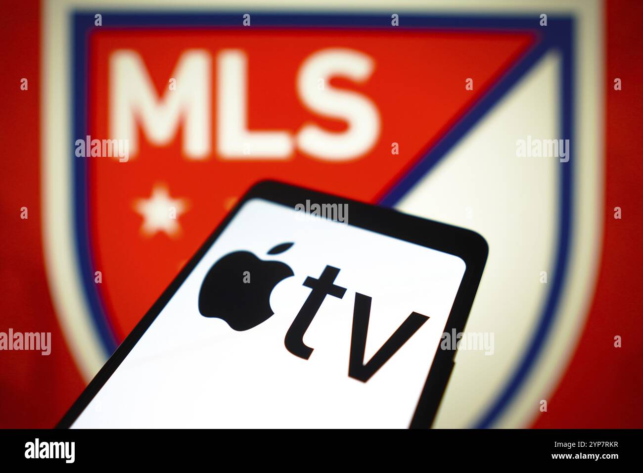 In questa immagine, il logo Apple TV viene visualizzato sullo schermo di uno smartphone e il logo Major League Soccer (MLS) sullo sfondo Foto Stock