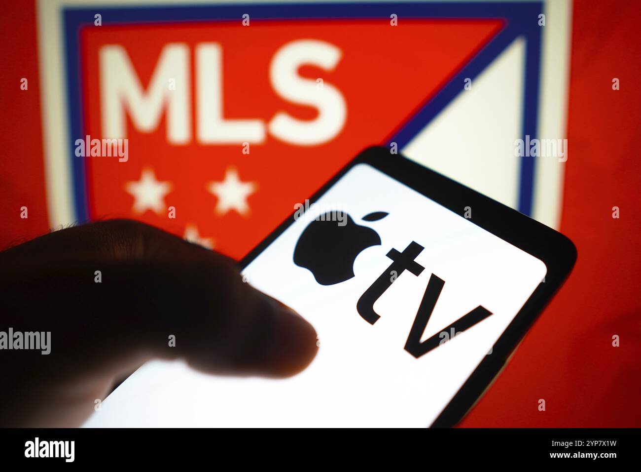 In questa immagine, il logo Apple TV viene visualizzato sullo schermo di uno smartphone e il logo Major League Soccer (MLS) sullo sfondo Foto Stock