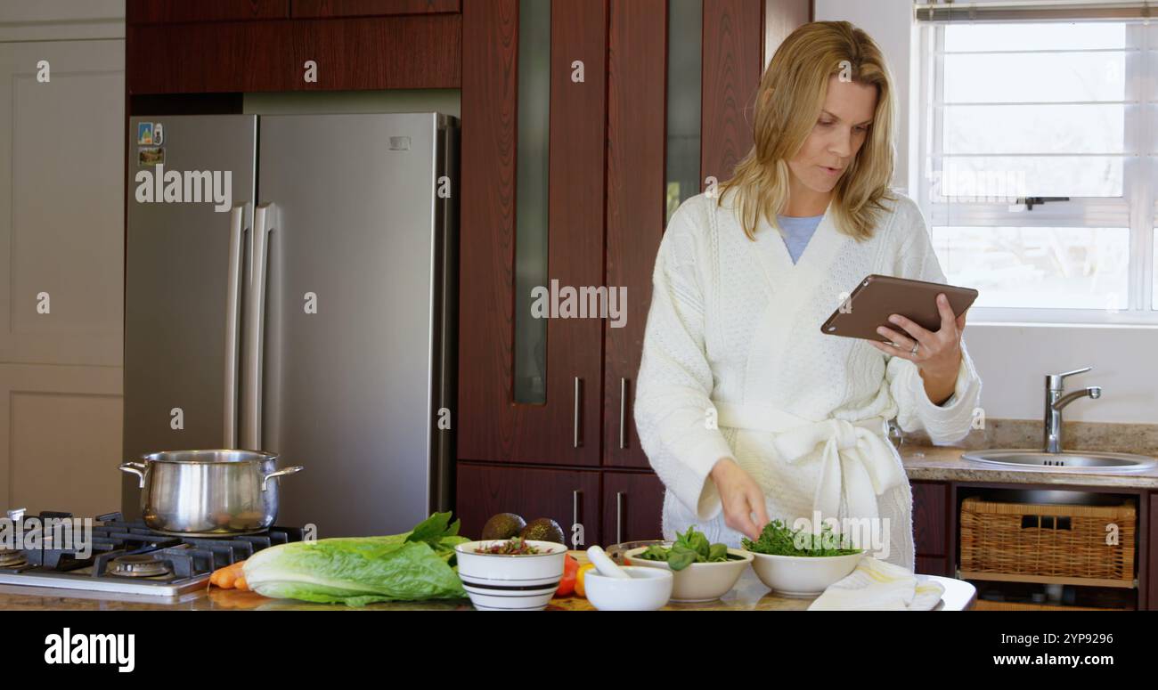 Donna che controlla la ricetta su un tablet digitale in cucina a casa Foto Stock