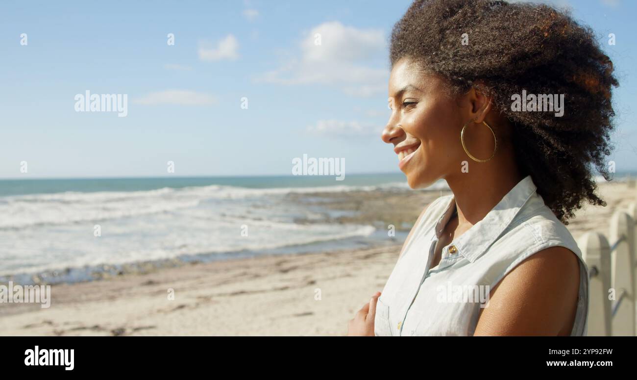 Donna in piedi con le braccia incrociate sulla spiaggia in una giornata di sole 4K Foto Stock