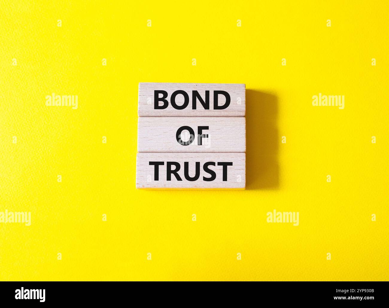 Simbolo del legame di fiducia. Blocchi di legno con parole Bond of Trust. Bellissimo sfondo giallo. Business e Bond of Trust. Copia spazio. Foto Stock