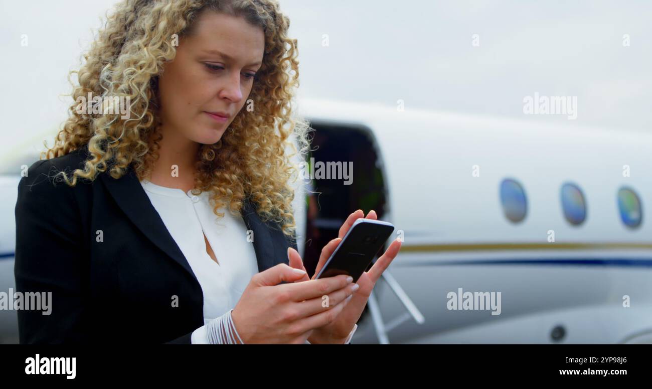 Bella donna d'affari che usa il telefono cellulare al terminal 4k Foto Stock