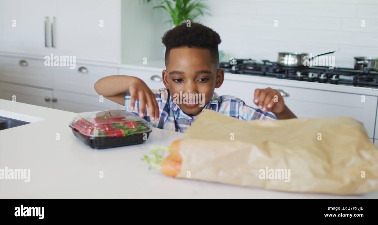 Felice ragazzo afroamericano disimballaggio alimentari in cucina Foto Stock