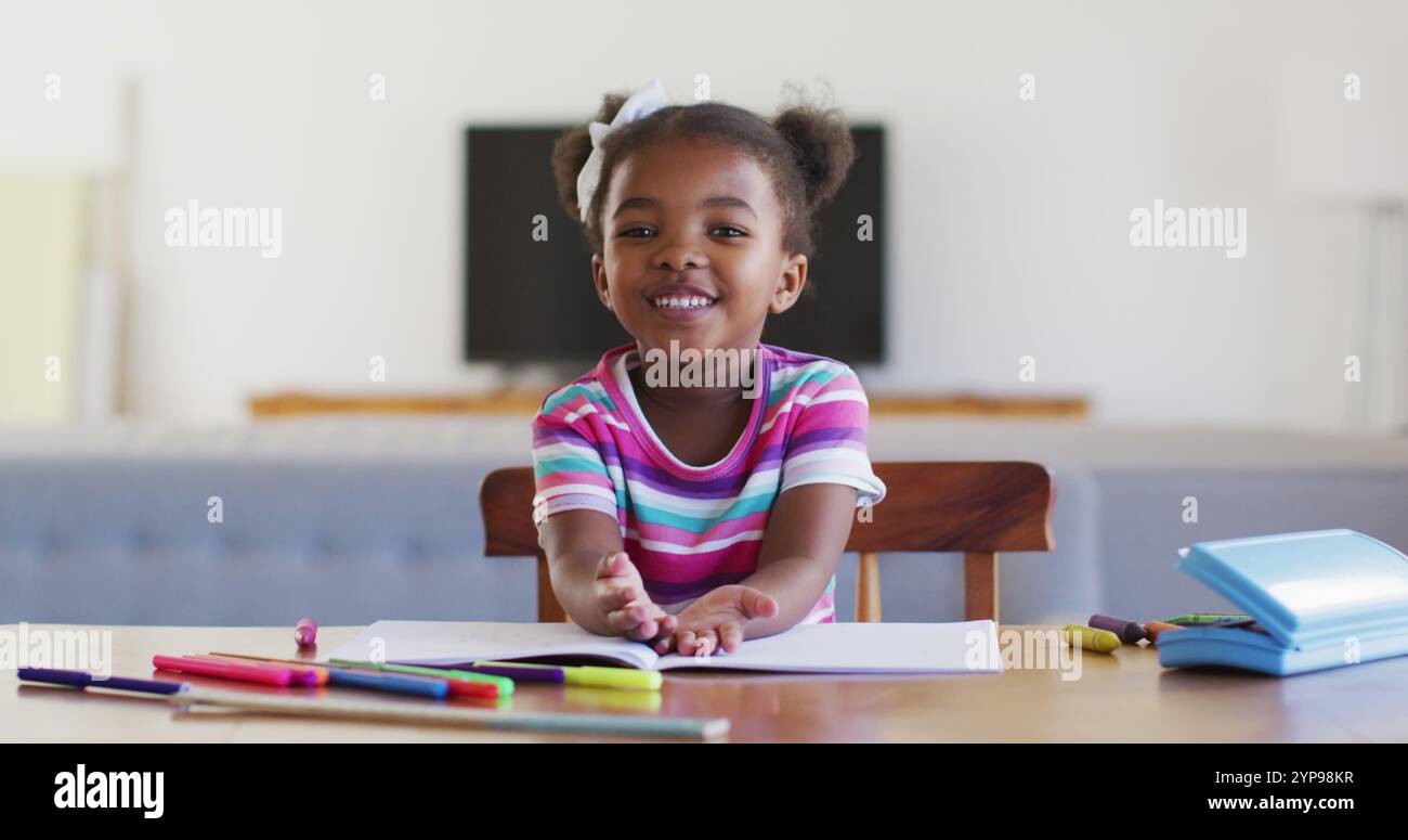 Felice ragazza afroamericana che ha una scuola online a casa Foto Stock