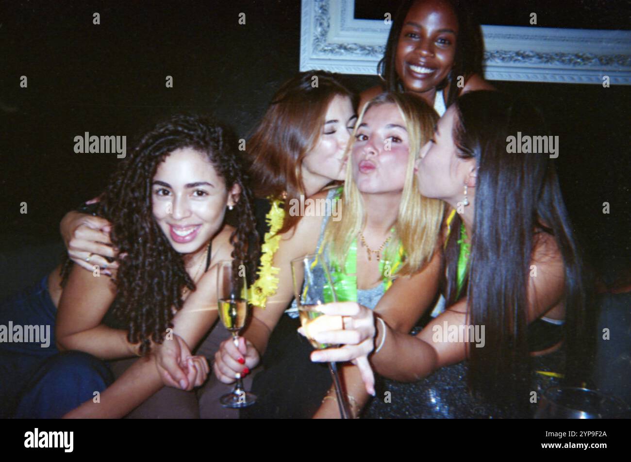 Un gruppo di amici che festeggiano con bevande e risate, catturati in uno stile cinematografico vintage. L'immagine trasuda amicizia e un'atmosfera da festa retrò. Foto Stock