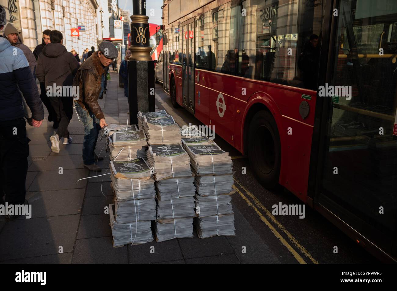 Pile di giornali serali si trovano sulla strada lungo Piccadilly, nel centro di Londra, Inghilterra, Regno Unito Foto Stock
