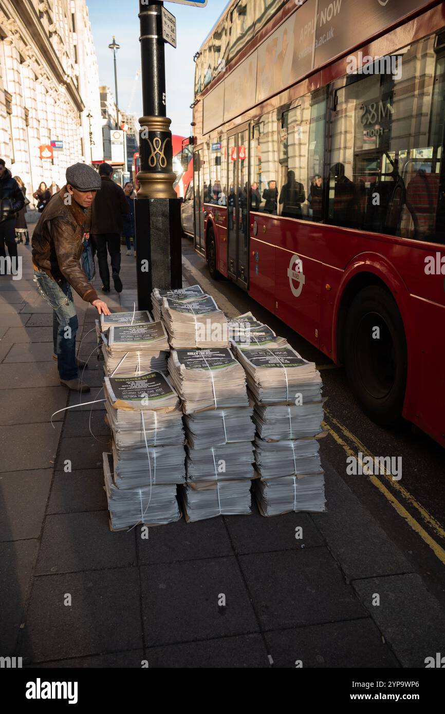 Pile di giornali serali si trovano sulla strada lungo Piccadilly, nel centro di Londra, Inghilterra, Regno Unito Foto Stock
