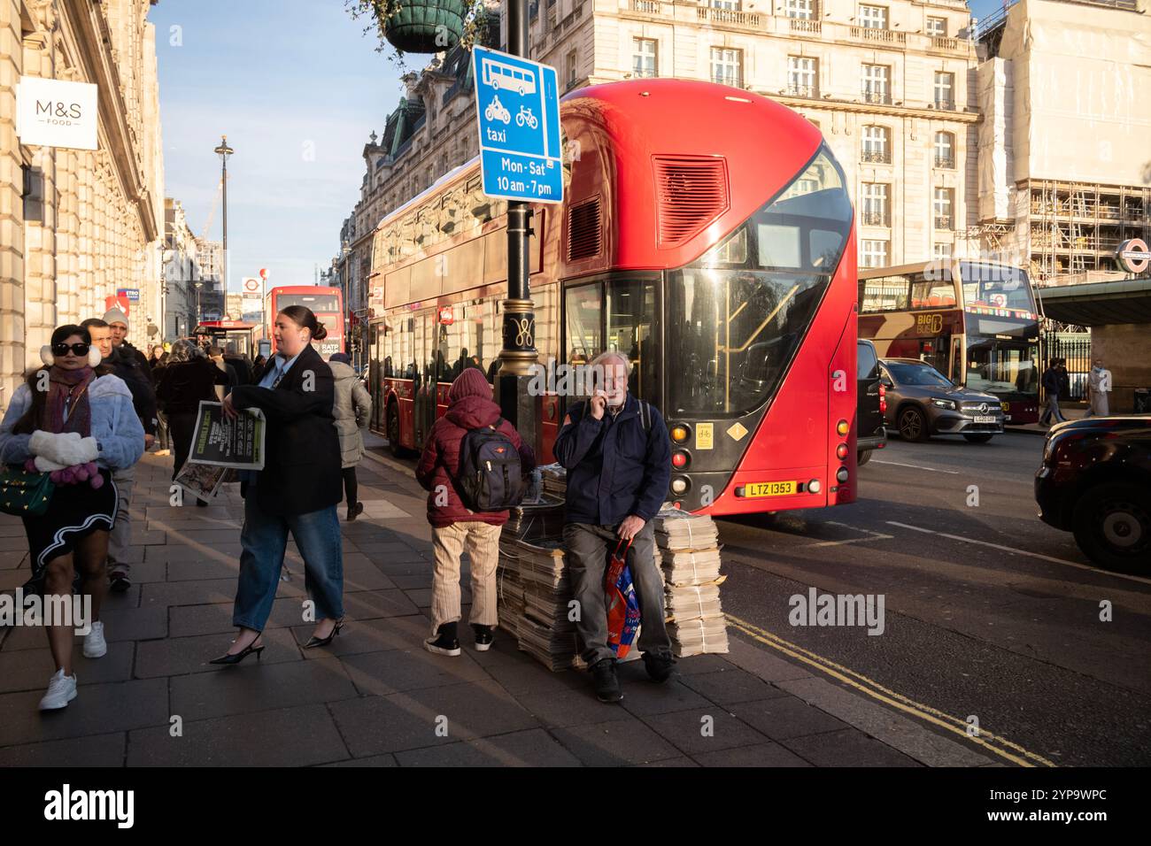 Pile di giornali serali si trovano sulla strada lungo Piccadilly, nel centro di Londra, Inghilterra, Regno Unito Foto Stock