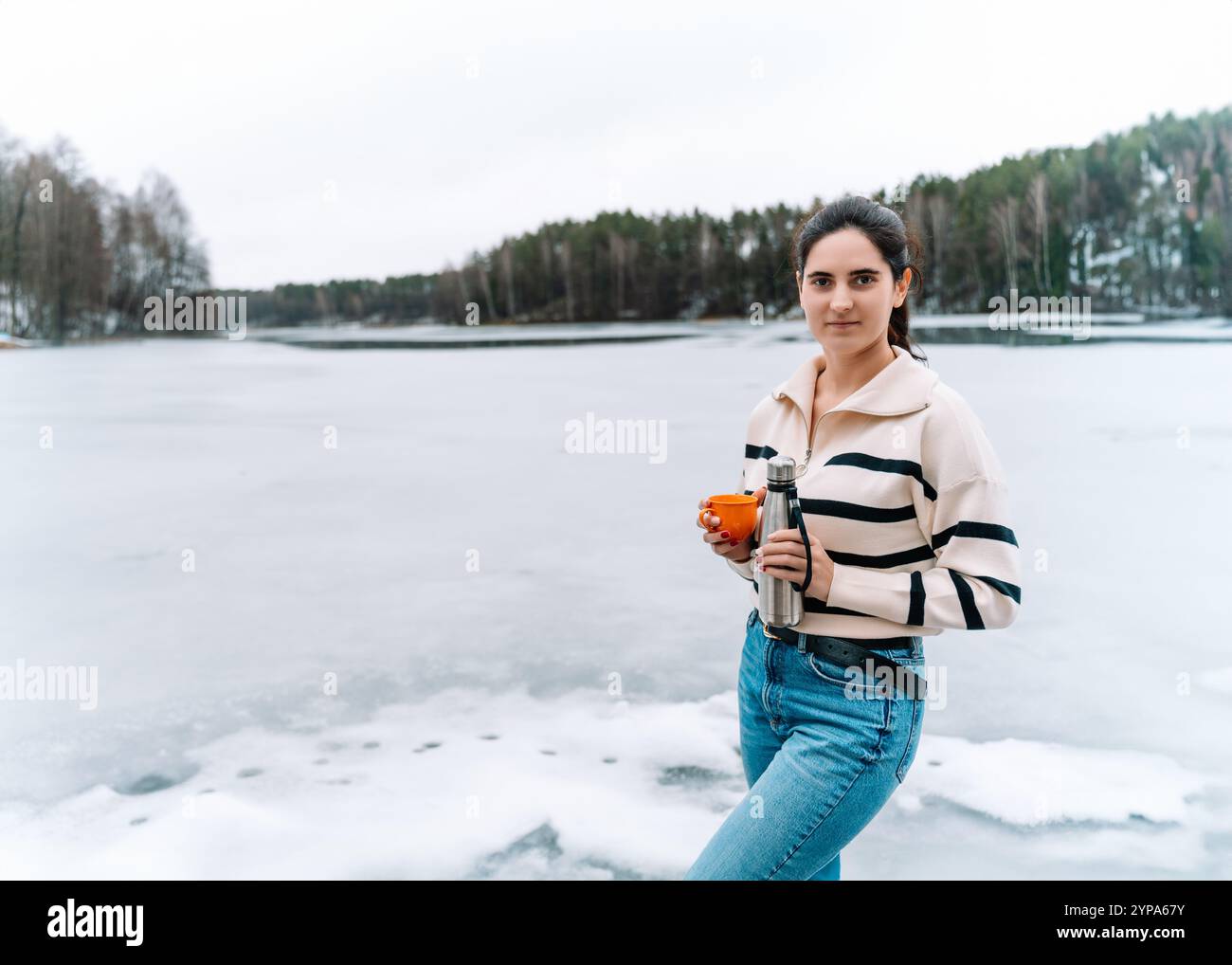giovane donna con thermos e tazza di caffè o tè durante la passeggiata invernale Foto Stock