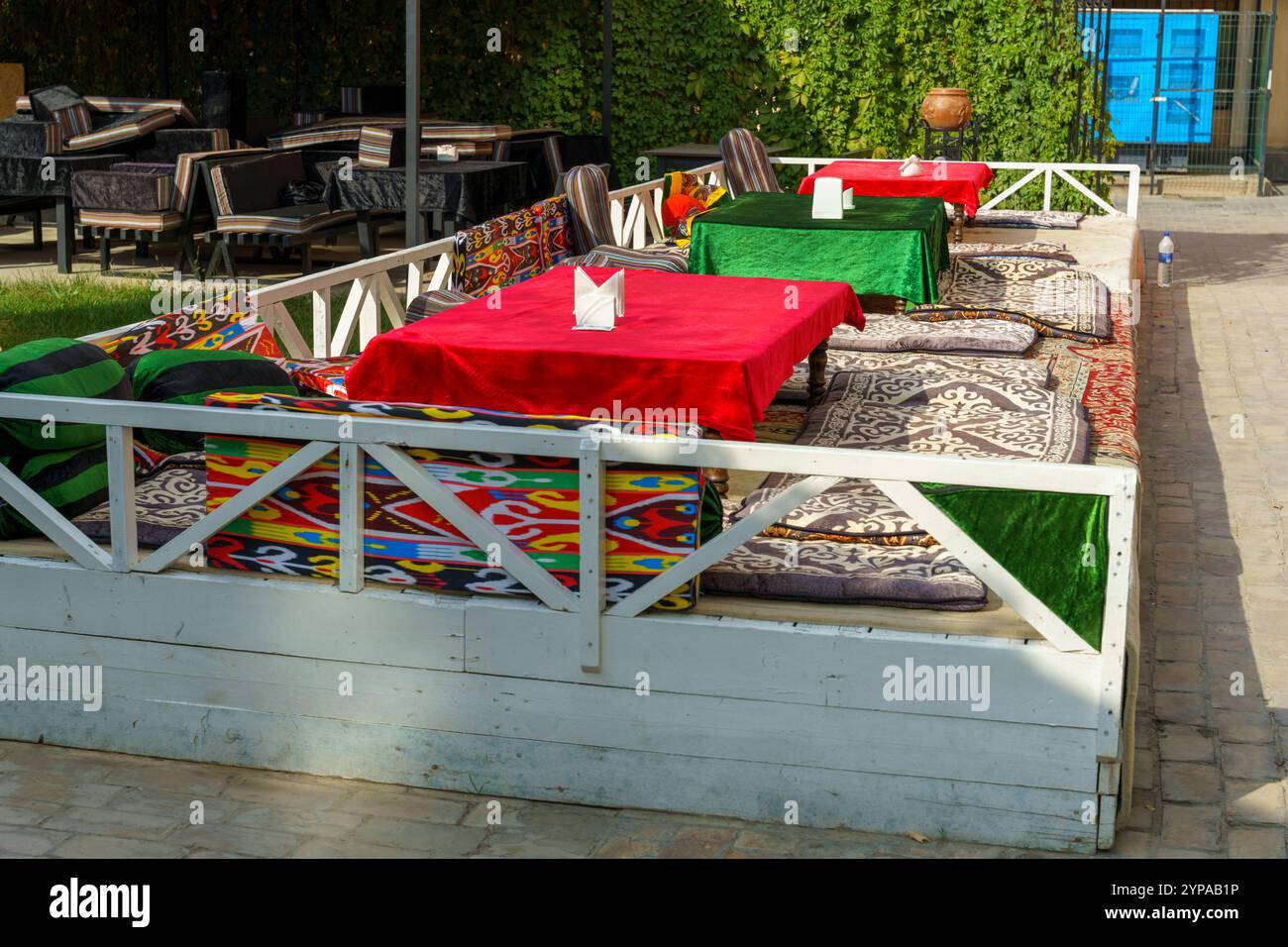 Un patio con una recinzione bianca e cuscini colorati Foto Stock