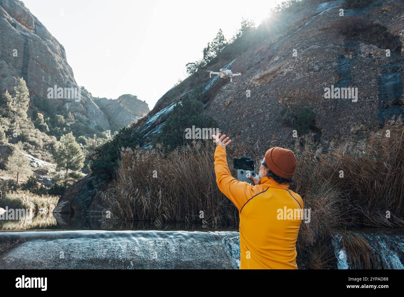 Viaggiatore che vola con un drone in un'area forestale utilizzando il telecomando. Foto Stock