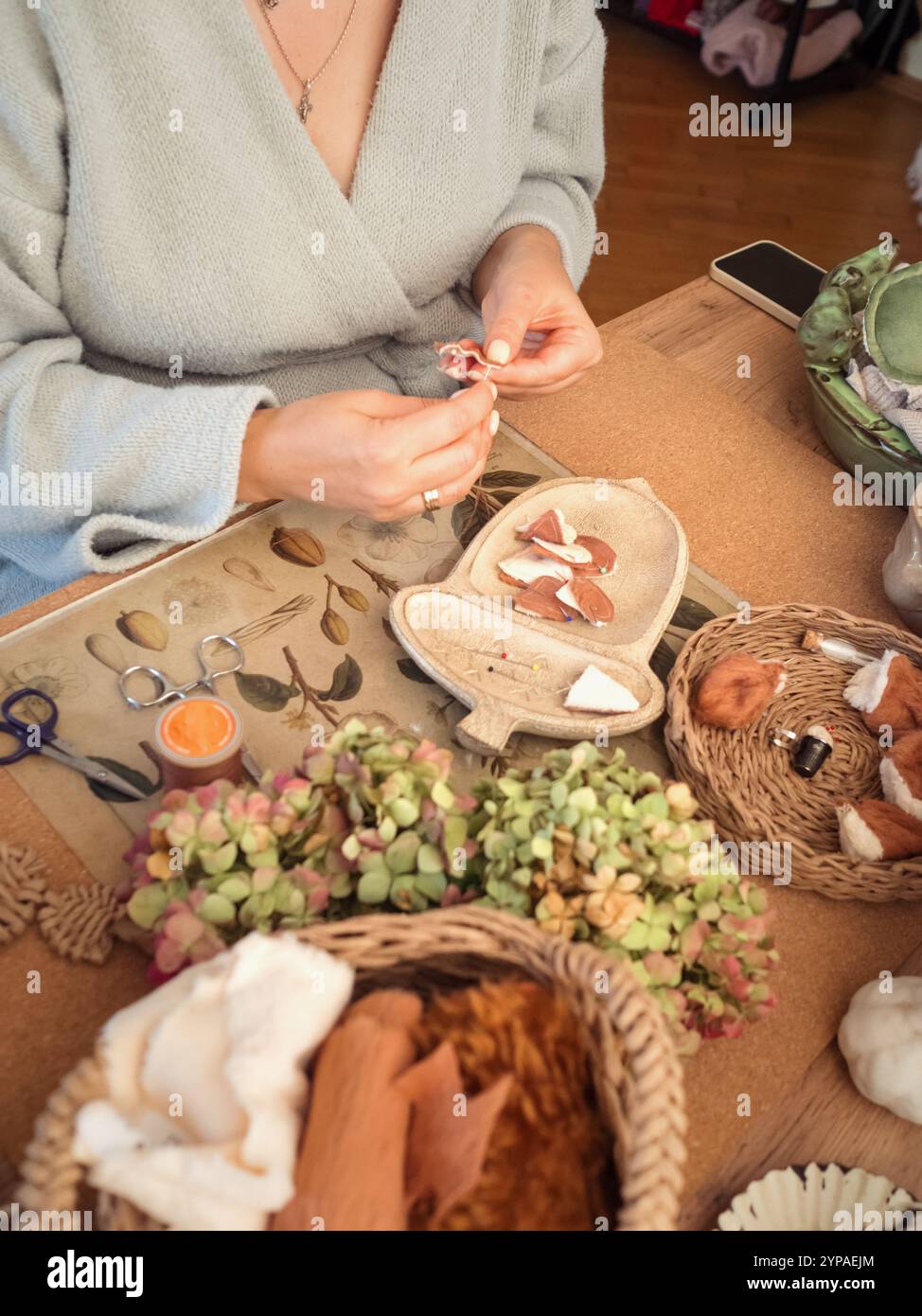 Donna che cucisce alla scrivania con tessuti e strumenti per la lavorazione Foto Stock