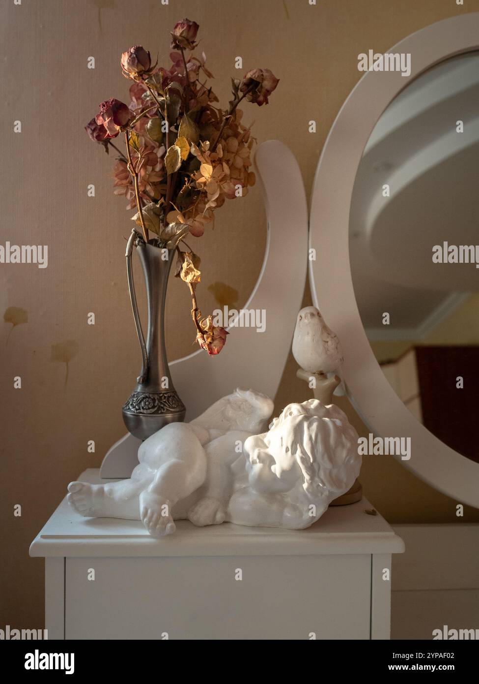 Camera da letto vintage con rose secche, specchio e una statuetta d'angelo Foto Stock