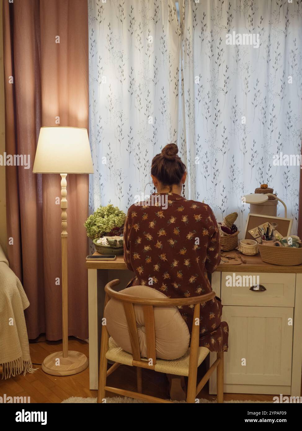 Donna che lavora alla sua scrivania nell'accogliente camera da letto, ad angolo verticale Foto Stock