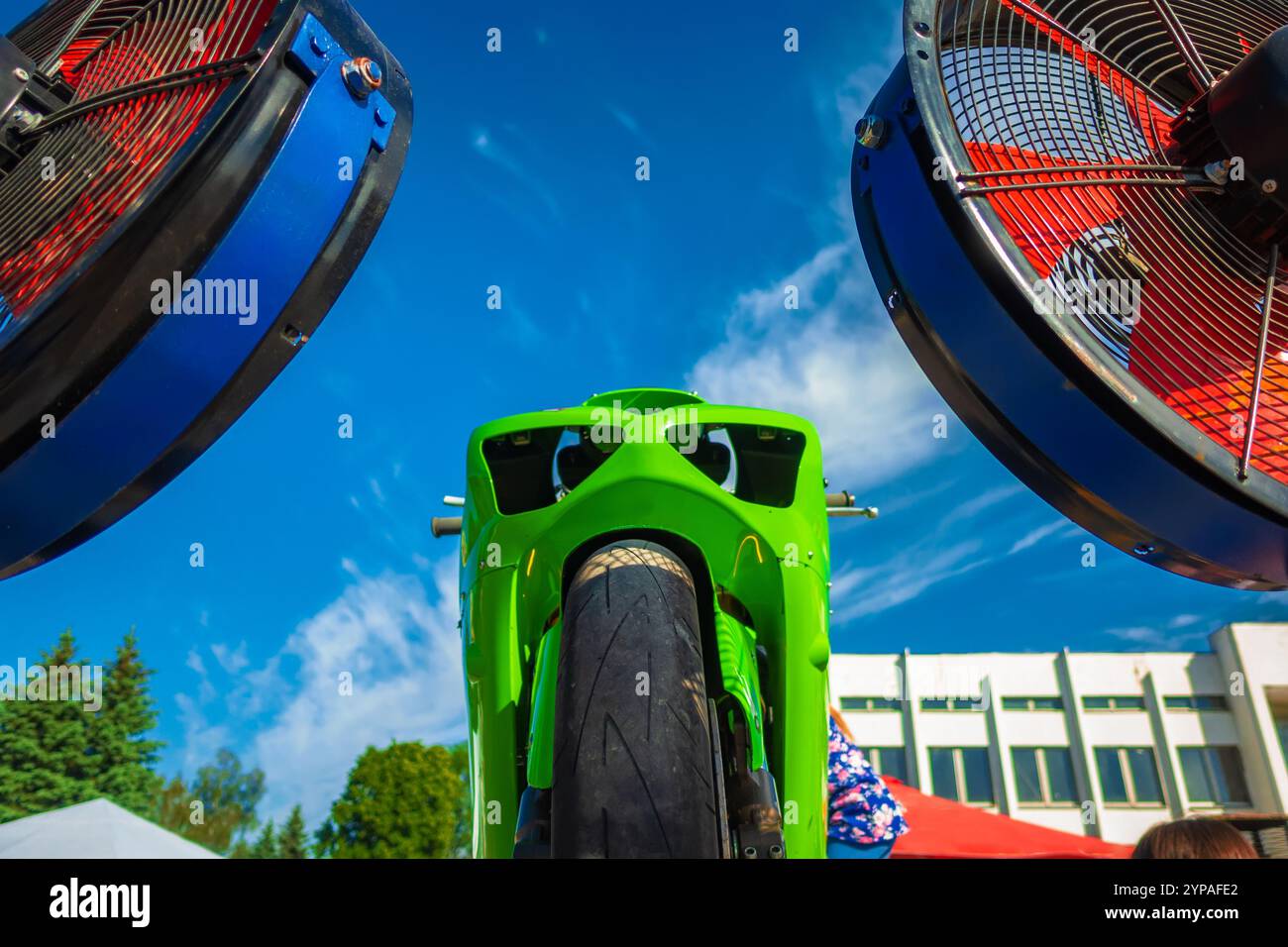 Lame rosse di un fan industriale sullo sfondo di una motocicletta sportiva. Foto Stock