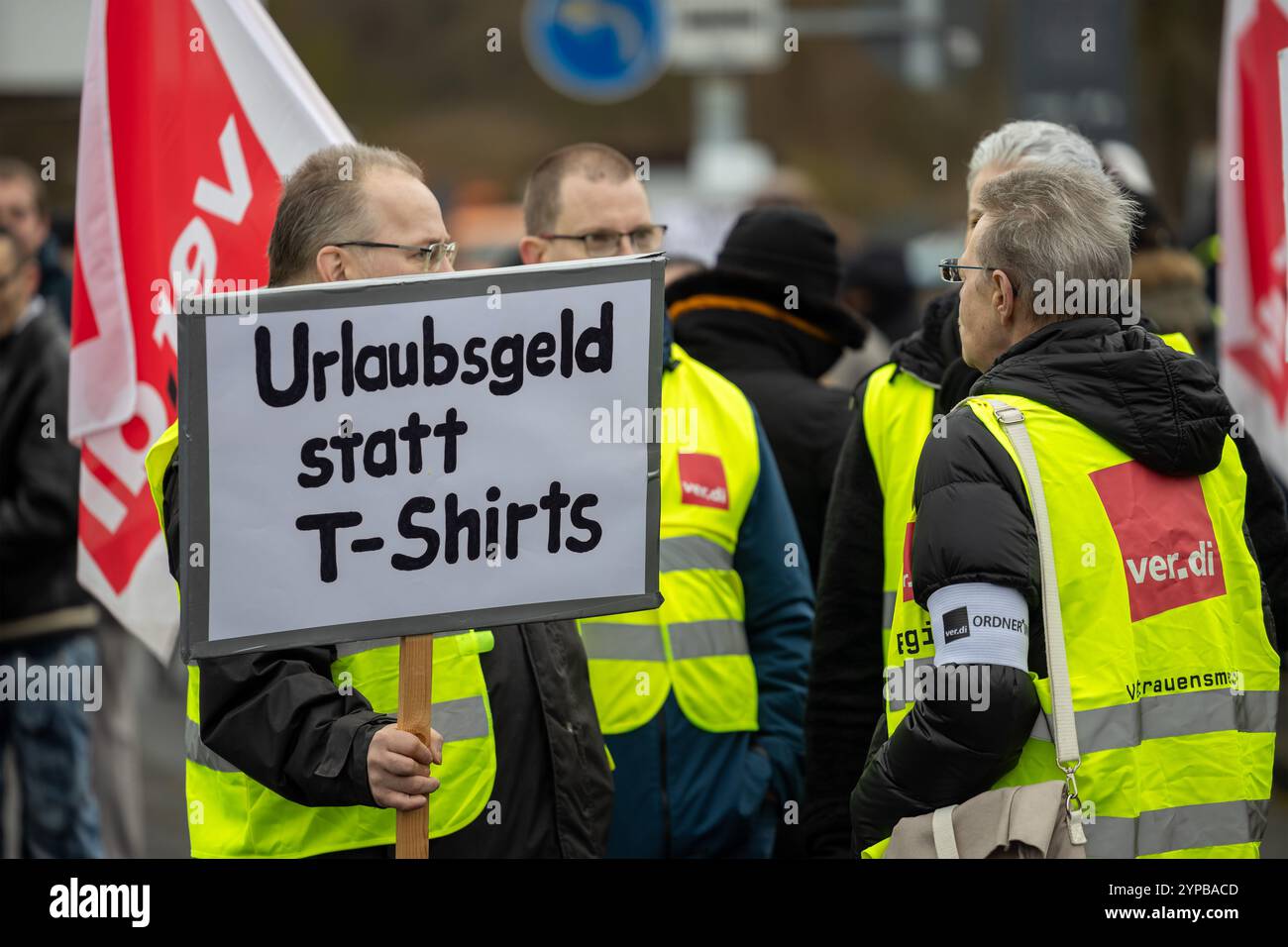29 novembre 2024, Assia, Bad Hersfeld: Sciopero dei partecipanti con un cartello che dice: "Paga le vacanze invece delle magliette". In occasione del giorno dello sconto del Black Friday, circa 400 - 500 dipendenti Amazon dalla Germania colpiscono con colleghi provenienti da Stati Uniti, Svezia, Regno Unito e Italia presso il centro internazionale di protesta di Bad Hersfeld. Insieme, vogliono attirare l'attenzione sulle condizioni di lavoro ingiuste e sulla mancanza di contrattazione collettiva in Amazon. L'azione è stata organizzata dalla United Services Union (ver.di) e dall'organizzazione globale dei sindacati dei servizi UNI Global Union. Foto: Christian Ladem Foto Stock