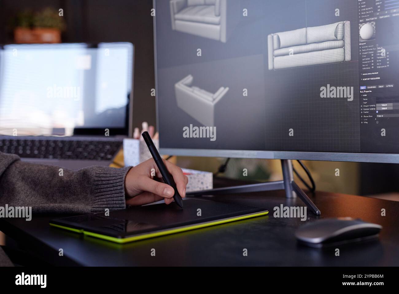 Singolo utente che utilizza un tablet grafico per creare modelli 3D dettagliati in un moderno studio di progettazione. Schermi di computer che visualizzano rendering di modelli di divani in varie prospettive Foto Stock