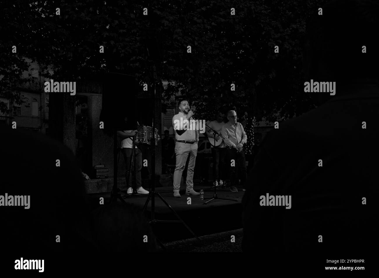 Vista monocromatica di uno spettacolo dal vivo durante i festival della città di Guimaraes, incorniciato da una folla attenta Foto Stock