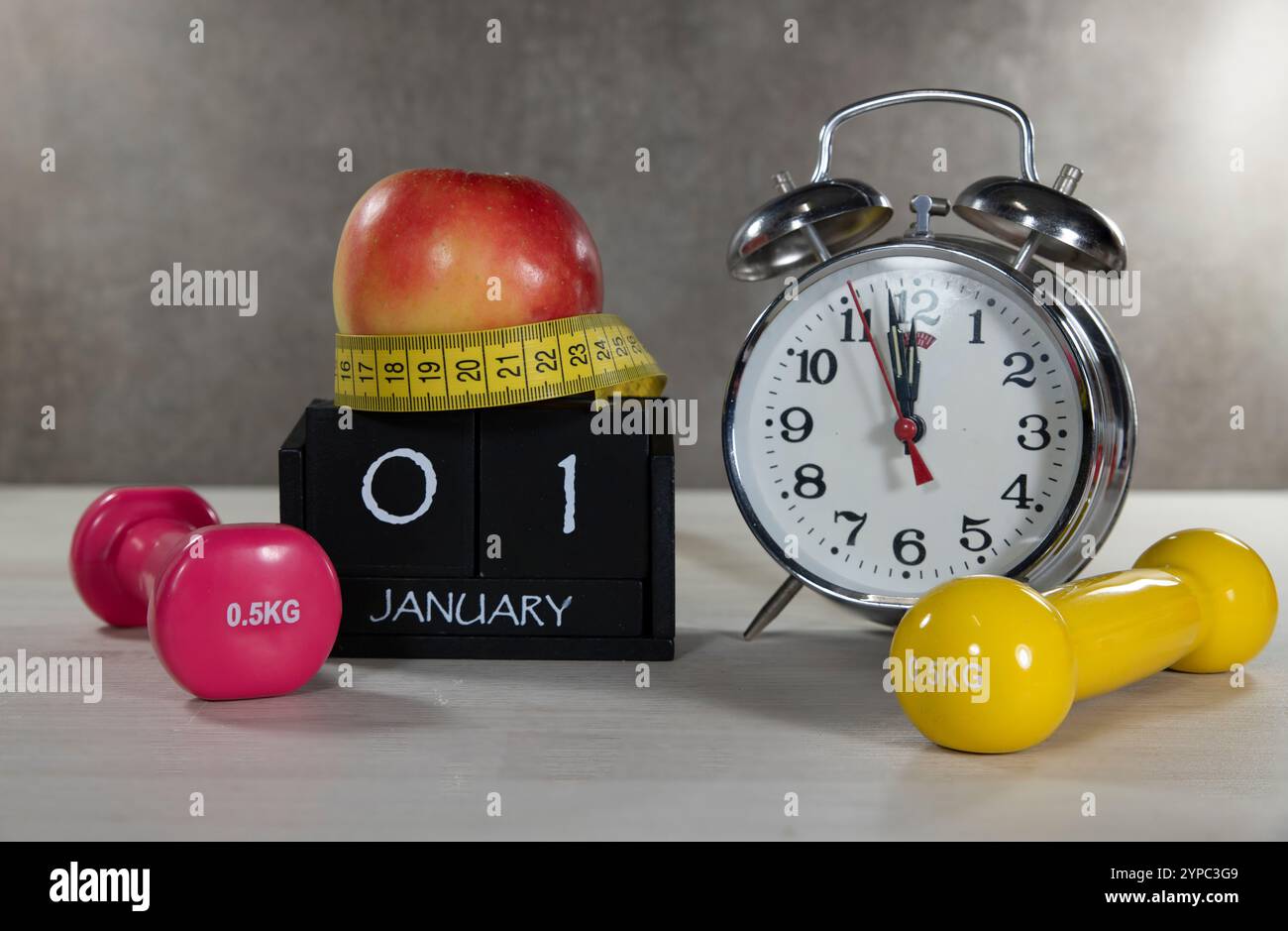Una composizione che simboleggia le risoluzioni di Capodanno con manubri, una mela, un metro a nastro e un orologio. Ideale per illustrare obiettivi di fitness e guarigione Foto Stock