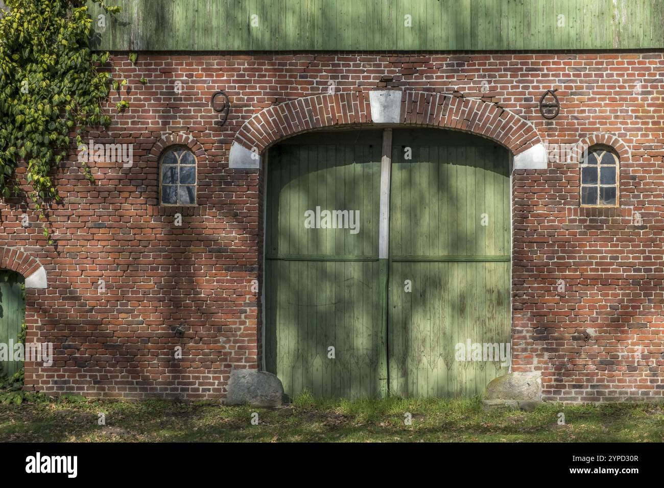 Un muro di mattoni con una grande porta di fienile verde e due piccole finestre, casa colonica, Muensterland, Renania settentrionale-Vestfalia, Germania, Europa Foto Stock