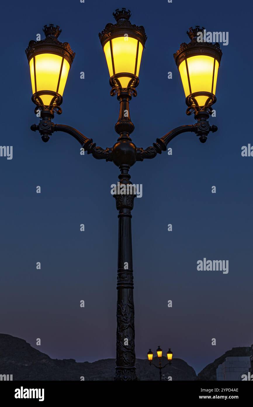 Lampada a candelabro illuminata a tre fiamme, presso il Palazzo del Sultano, Mascate, Penisola Araba, Sultanato dell'Oman Foto Stock