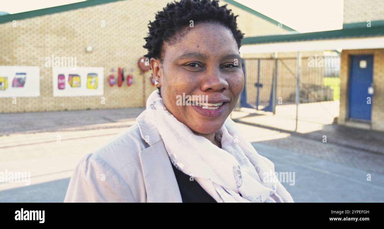 Primo piano ritratto di un'insegnante di scuola africana di mezza età con capelli corti e appuntiti che girano e l Foto Stock