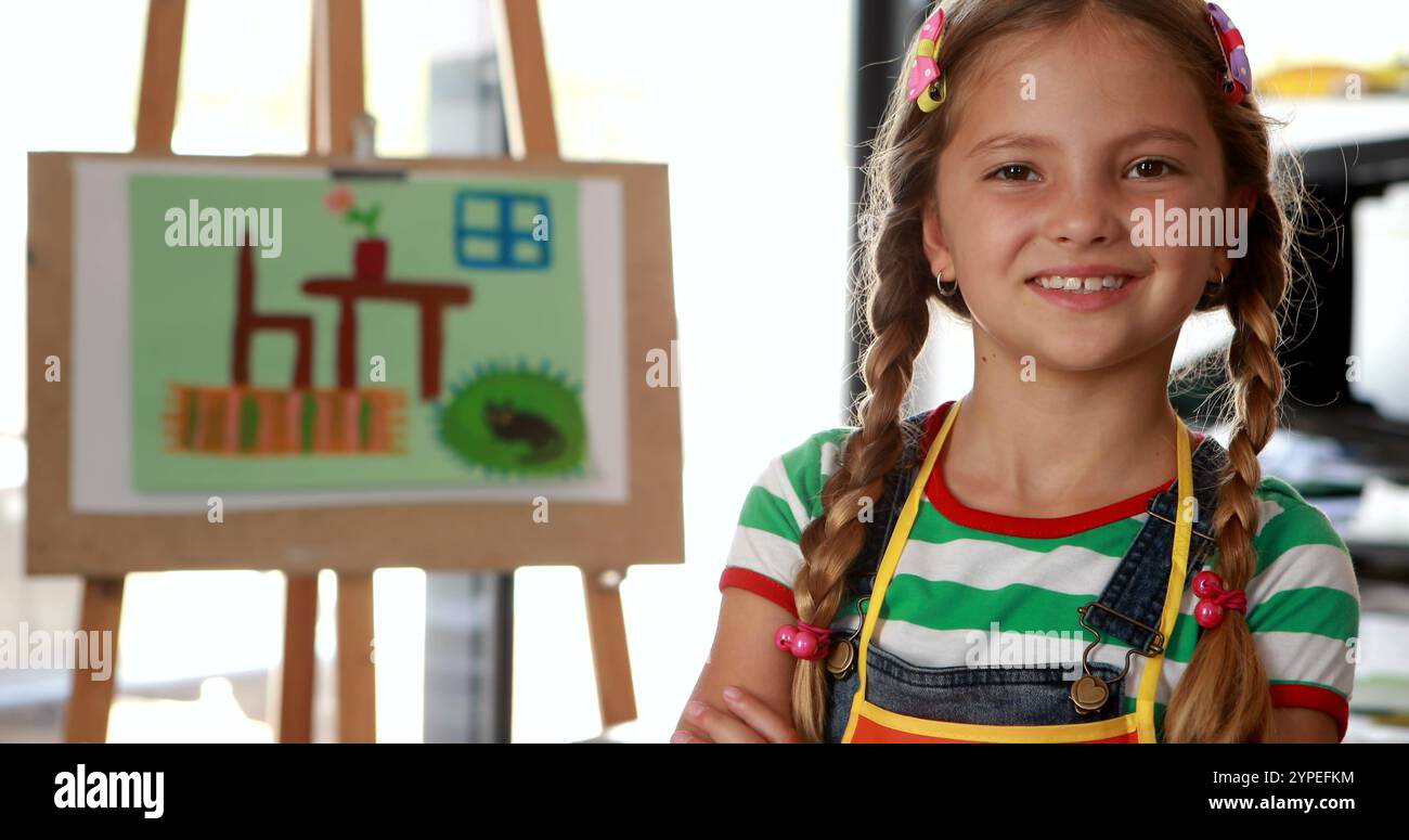 Ritratto di una studentessa carina in piedi con le braccia incrociate a tavola nella classe di disegno 4k Foto Stock
