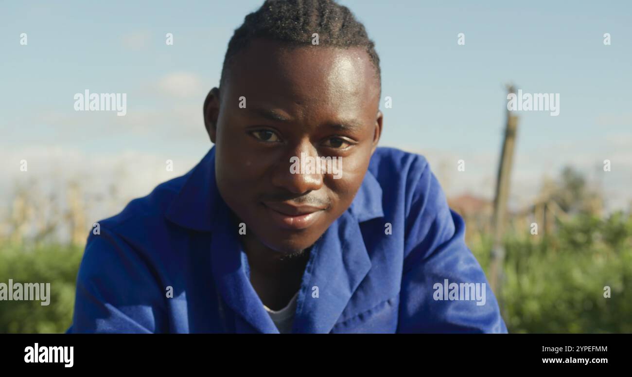 Ritratto di un giovane agricoltore afroamericano in un campo agricolo biologico, che controlla le colture Foto Stock