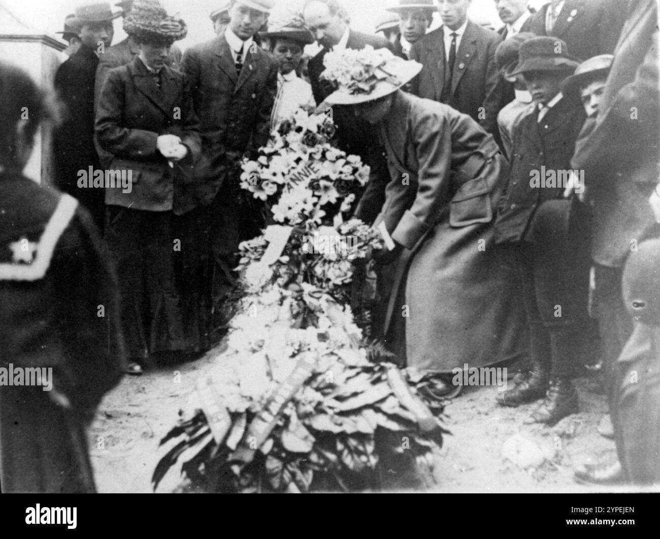 Donne, uomini e bambini si riuniscono intorno a una corona funebre in onore di Annie, vittima dell'incendio del Triangolo il 25 marzo 1911. Il Triangle Shirtwaist Factory Fire è stato uno dei peggiori incidenti industriali nella storia degli Stati Uniti. E' scoppiato un incendio al decimo piano dell'Asch Building. Le uscite antincendio erano chiuse a chiave, l'uscita antincendio inadeguata e le scale dei motori antincendio non erano abbastanza lunghe. 146 persone furono uccise, di cui 62 saltarono alla morte per evitare le fiamme. Foto Stock