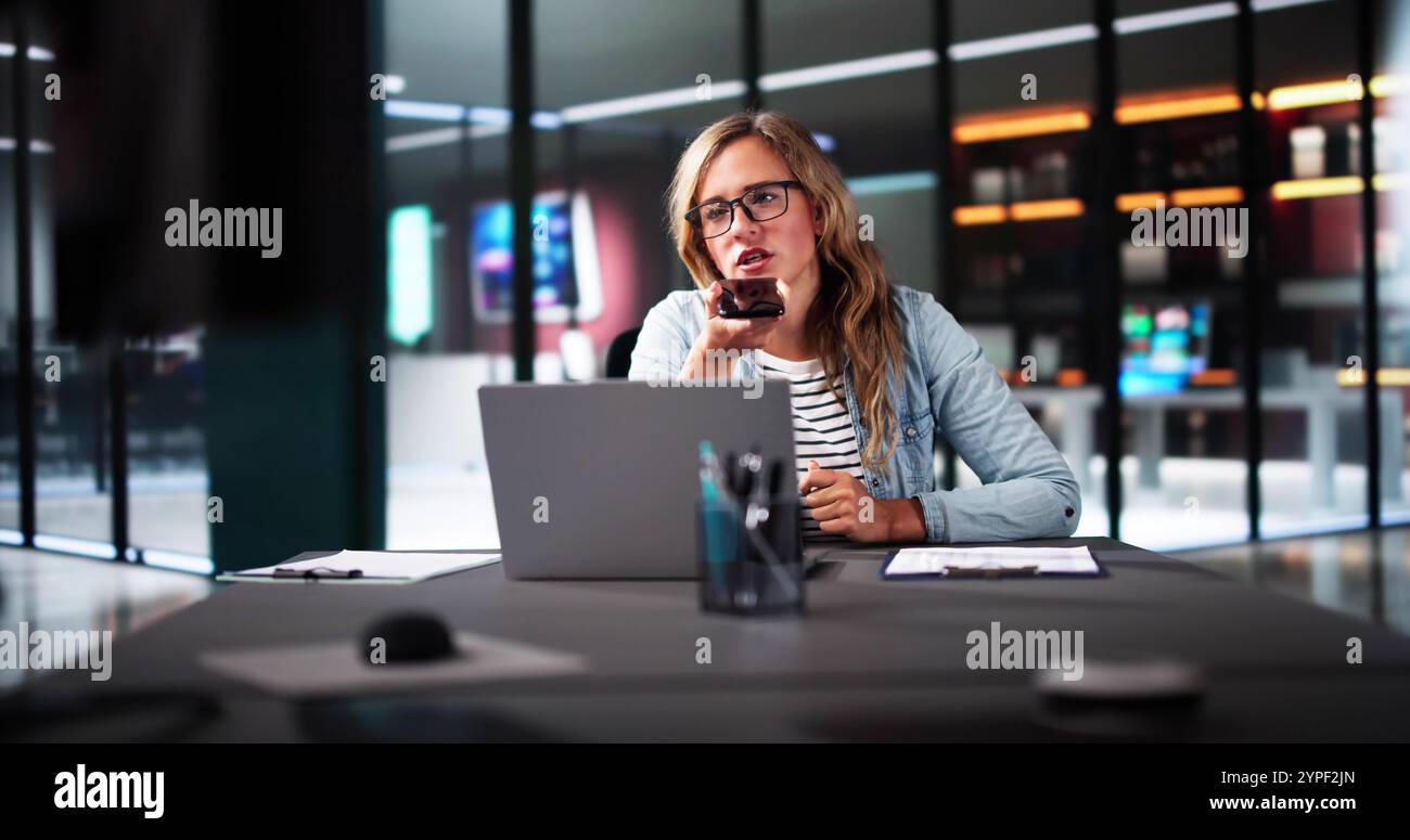 Donna d'affari professionista che utilizza l'app per smartphone per le chiamate client in un ufficio moderno con laptop e sorridente Foto Stock