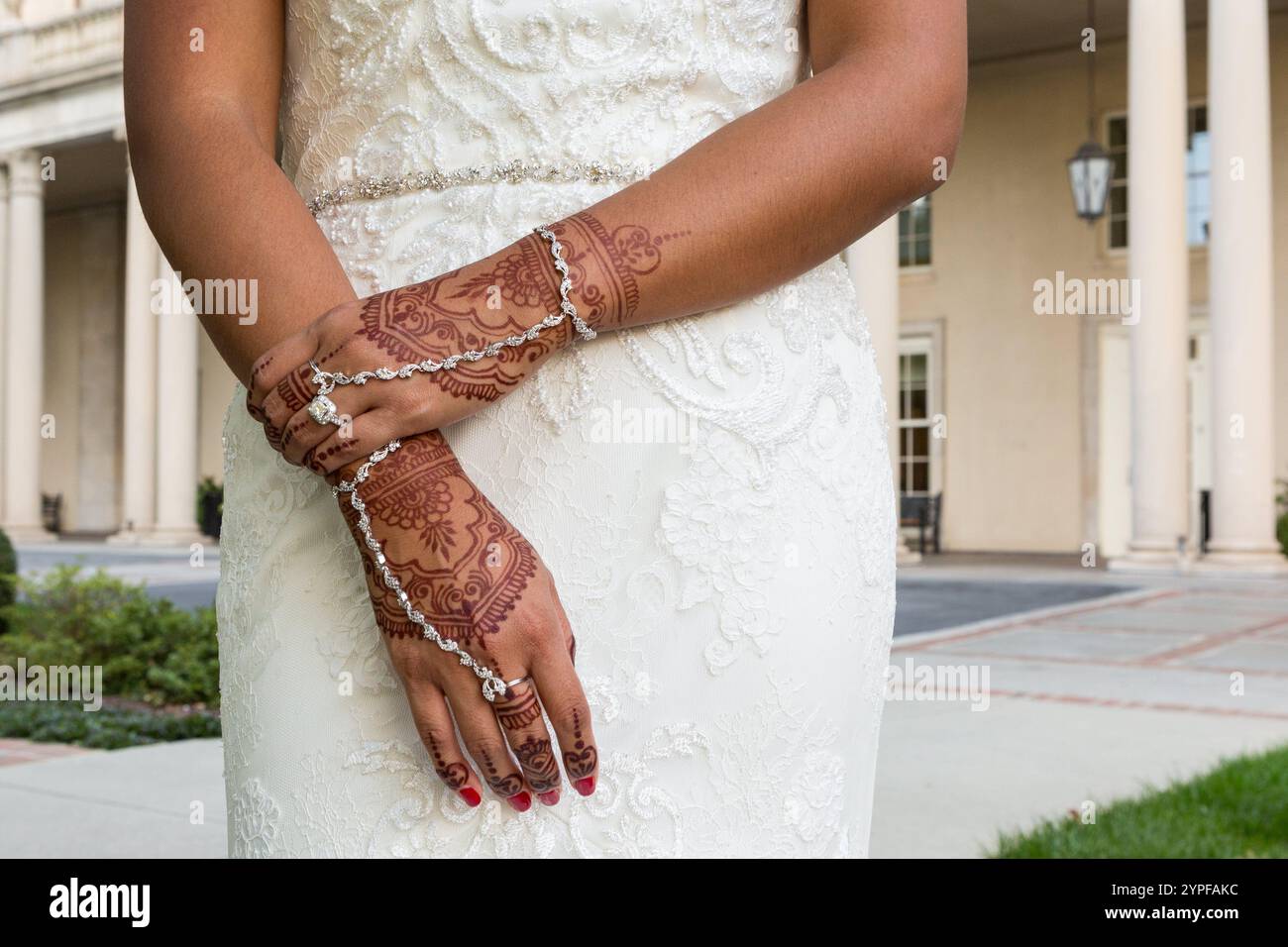 Primo piano delle mani della sposa indiana con abito bianco che mostra intricati disegni di Henna Foto Stock