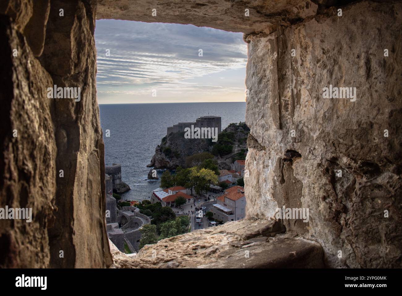 Imagen captada a través de una ventana de las murallas de Dubrovnik. La abertura de piedra actúa como marco Natural de la fortaleza de Lovrijenac. Foto Stock