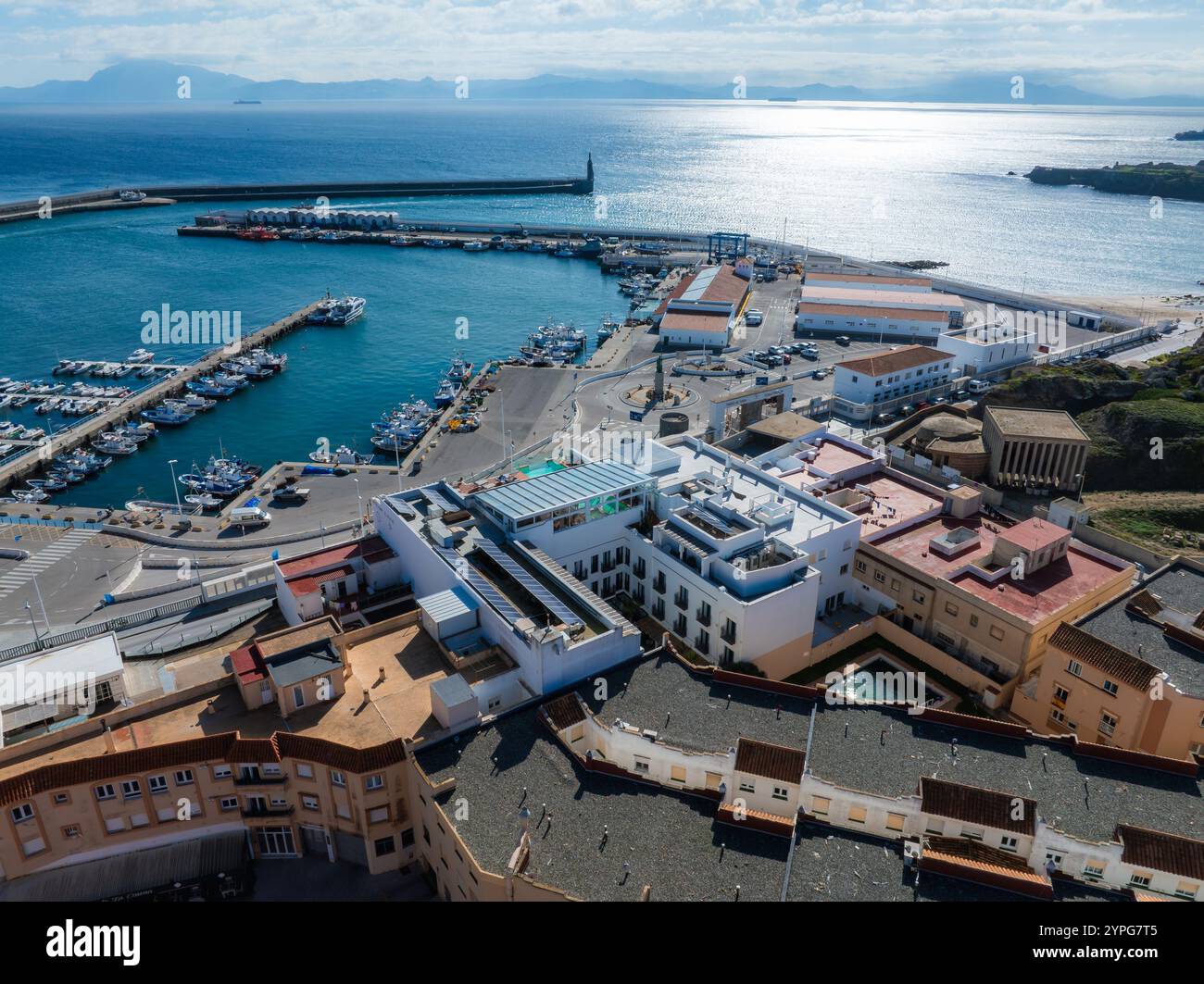 L'immagine mostra una vista aerea di Tarifa, Spagna, con un vivace porto con barche e yacht, circondato da edifici moderni e tradizionali. Foto Stock