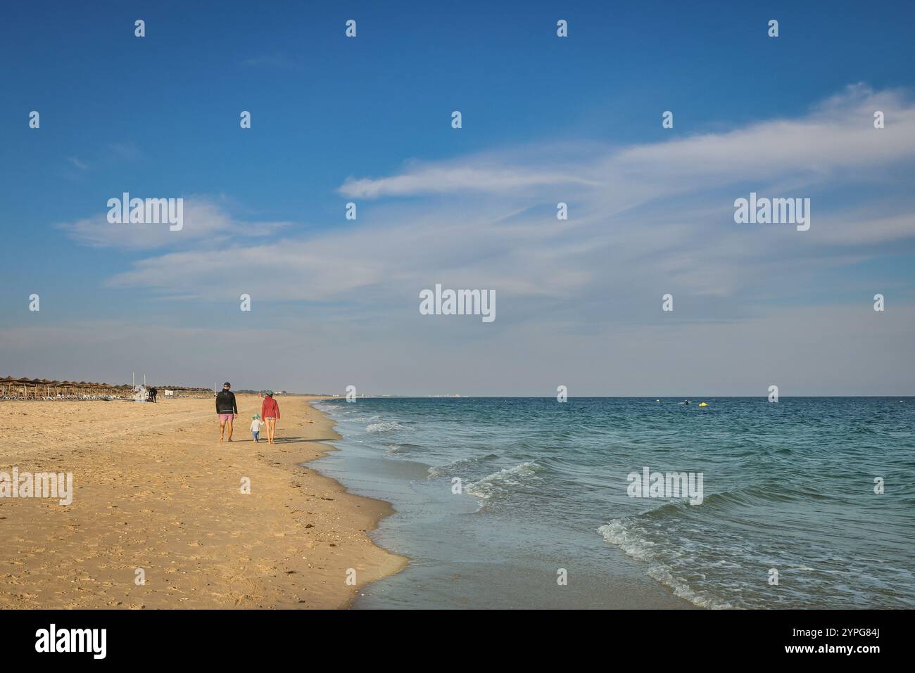 Passeggiate in spiaggia sotto il sole caldo a Cabanas Beach, Cabanas de Tavira, Algarve orientale, Portogallo Foto Stock