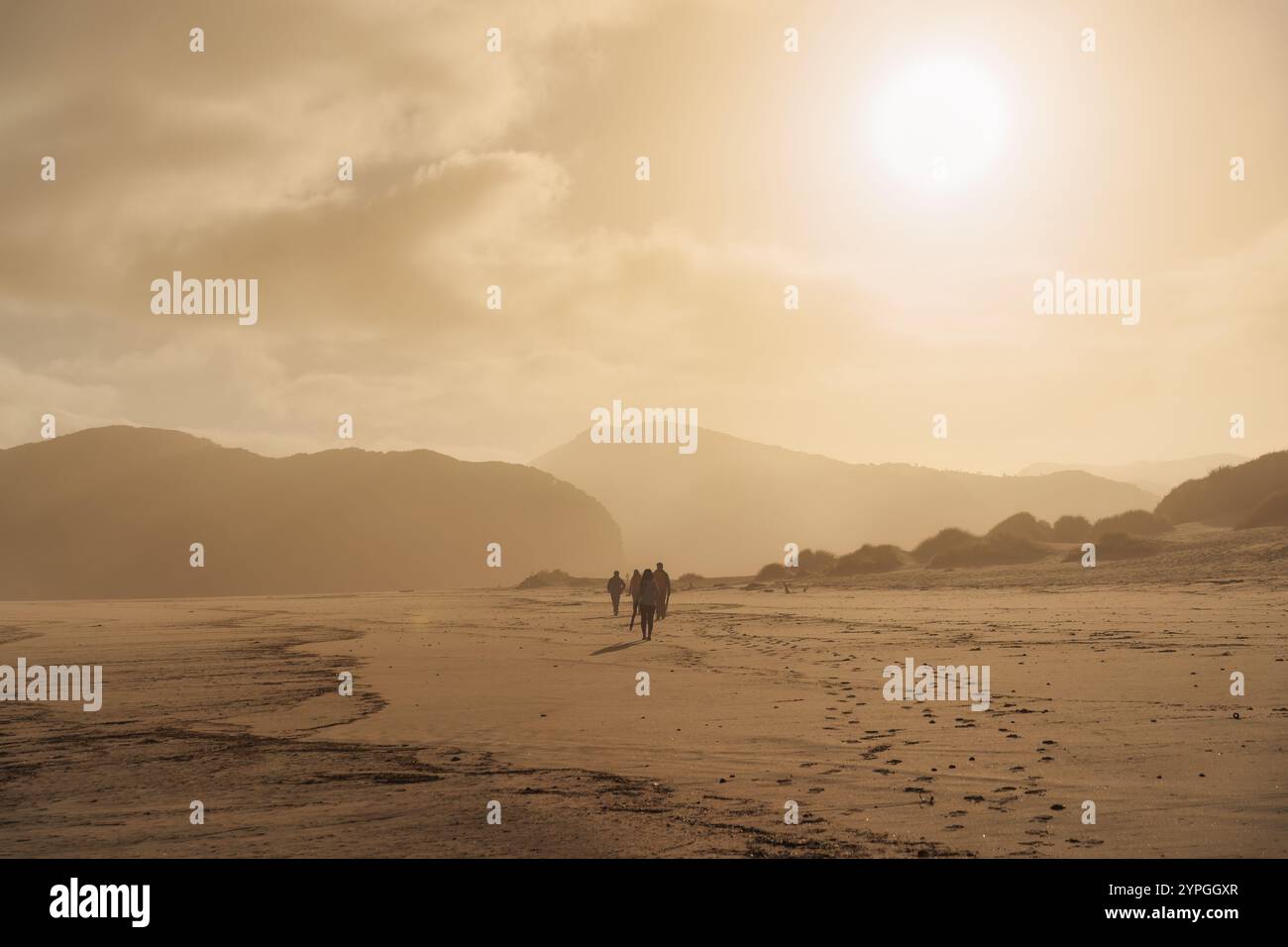 Splendida alba dorata sui turisti che camminano sulle dune di sabbia nella spiaggia di Wharariki sulla costa occidentale di Cape Farewell, nuova Zelanda Foto Stock
