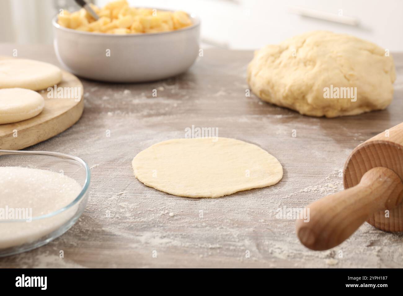 Preparazione di pirozhki (torte di pasticceria ripiena). Pezzi di impasto su un tavolo di legno, primo piano Foto Stock